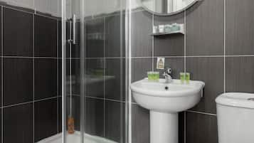 A modern bathroom with a glass-enclosed shower, a pedestal sink, and a toilet.
