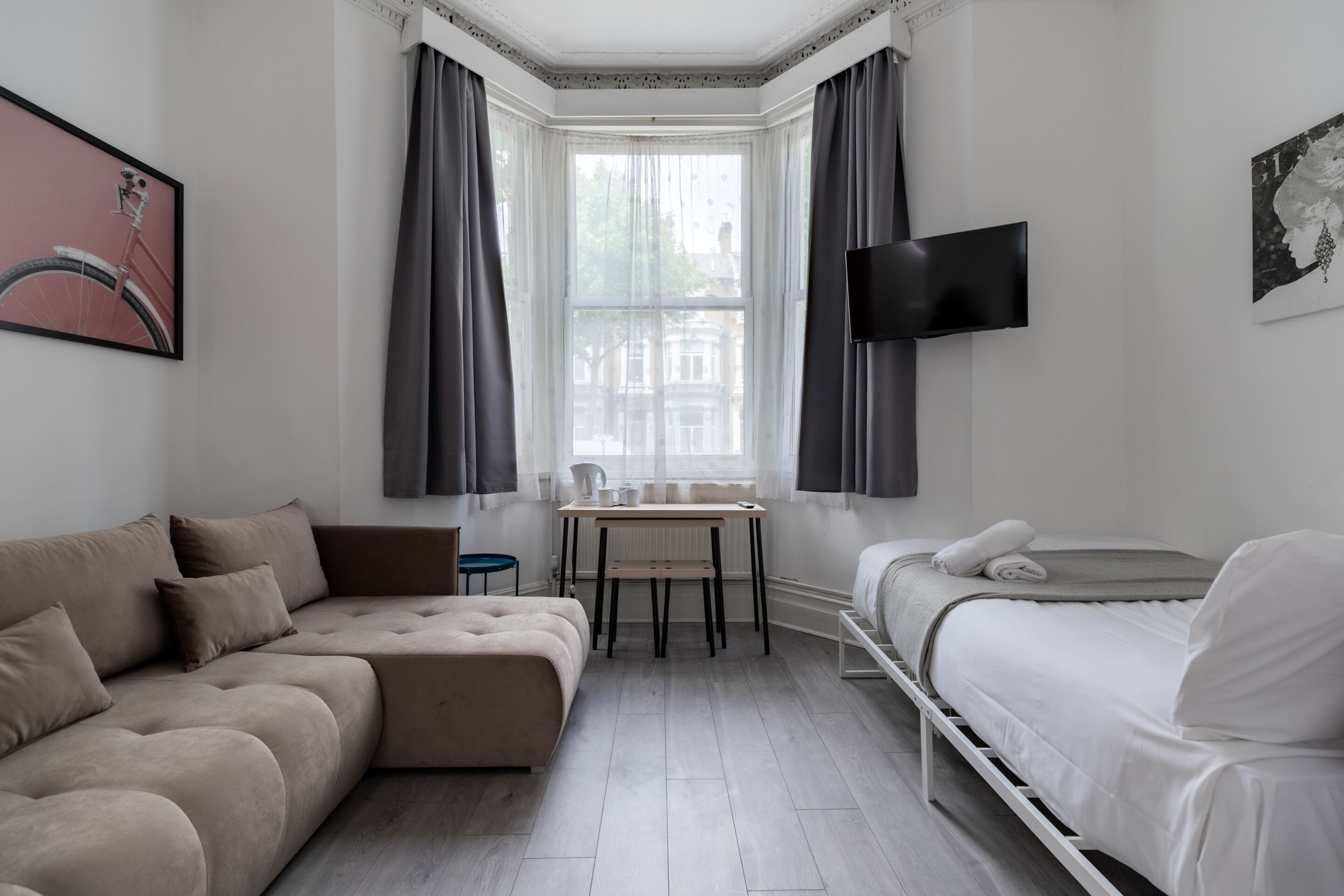 A modern bedroom with a sofa, a bed, a desk, and a TV.