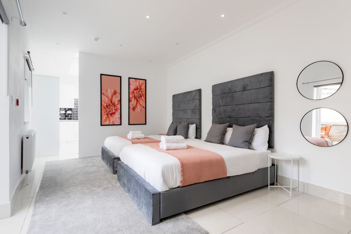 A modern bedroom with a large bed, two side tables, and artwork on the walls.