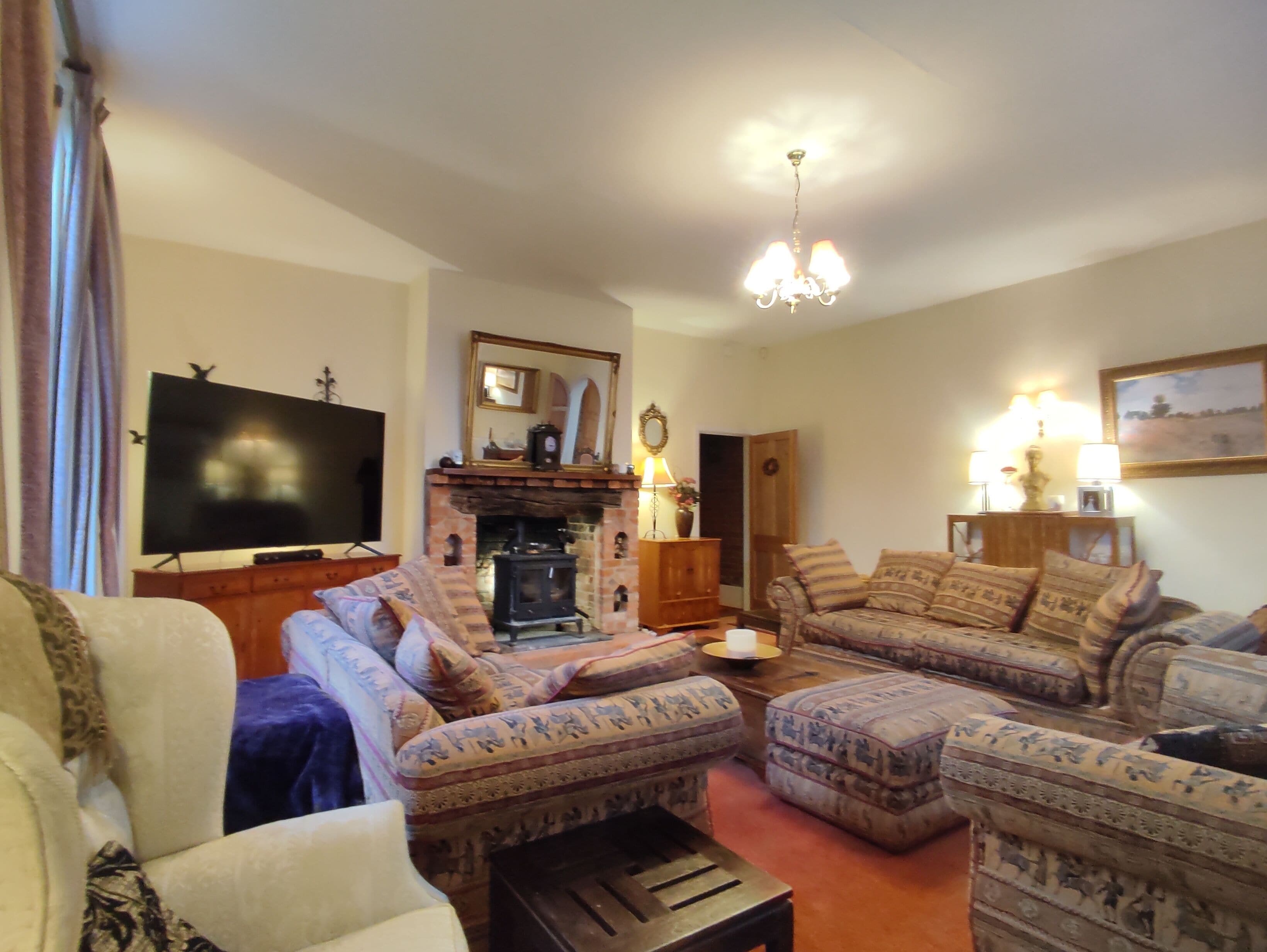 A living room with a fireplace, a television, and patterned furniture.