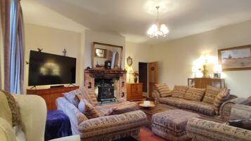 A living room with a fireplace, a television, and patterned furniture.