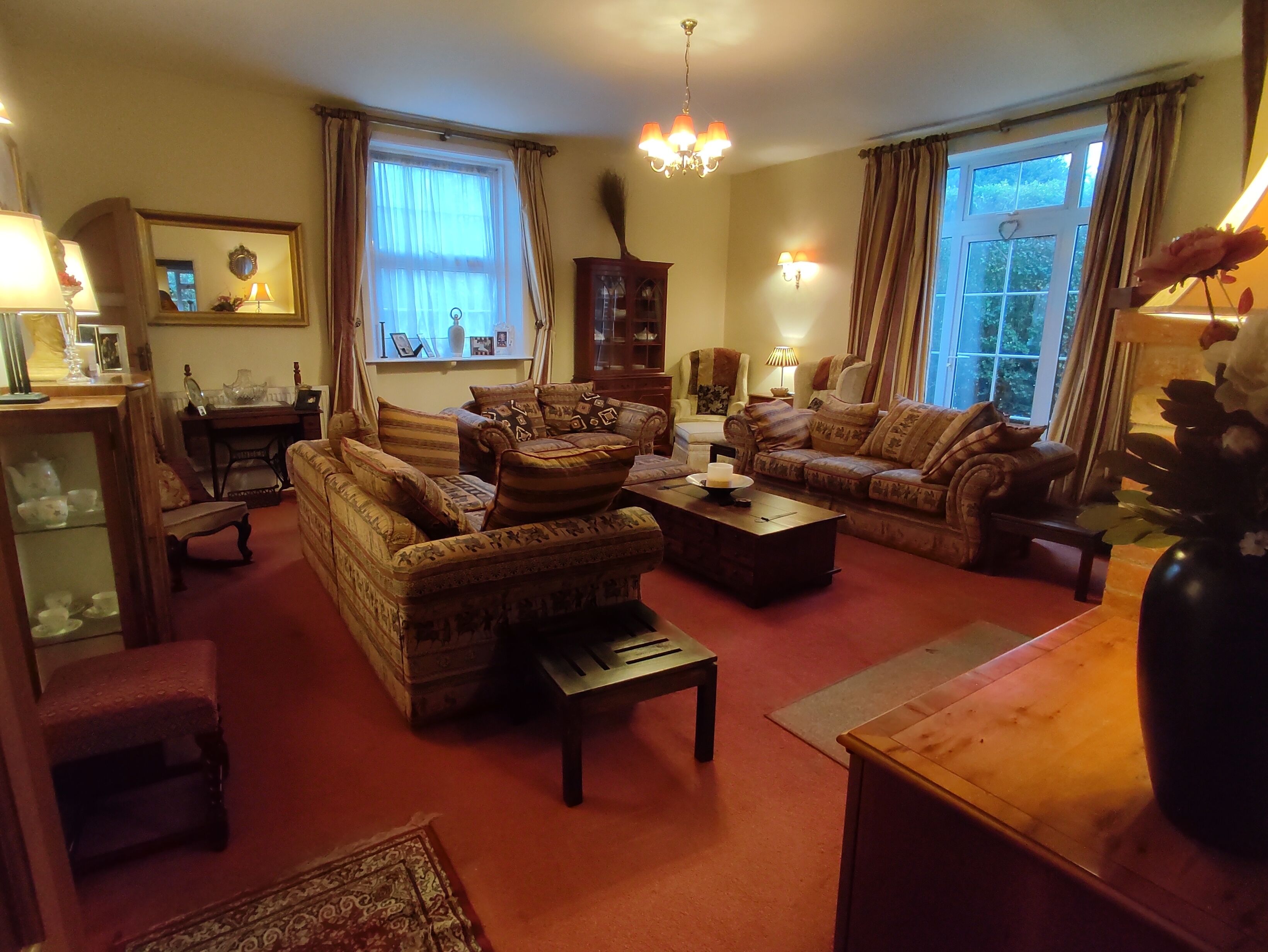 A traditional living room with patterned sofas, a wooden coffee table, and a chandelier.