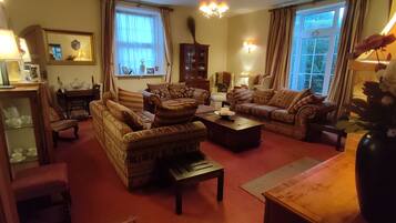 A traditional living room with patterned sofas, a wooden coffee table, and a chandelier.