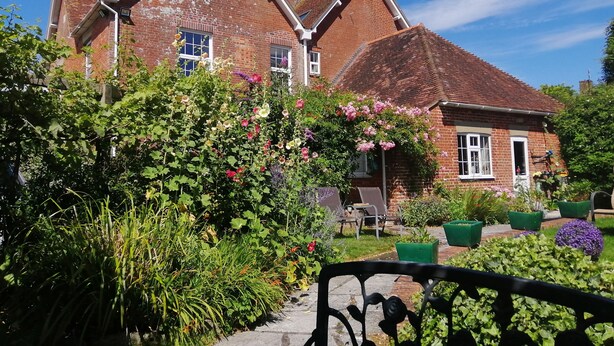 A traditional brick house with a garden in front, featuring a pathway and a metal fence. - The Cheese House (Salisbury)