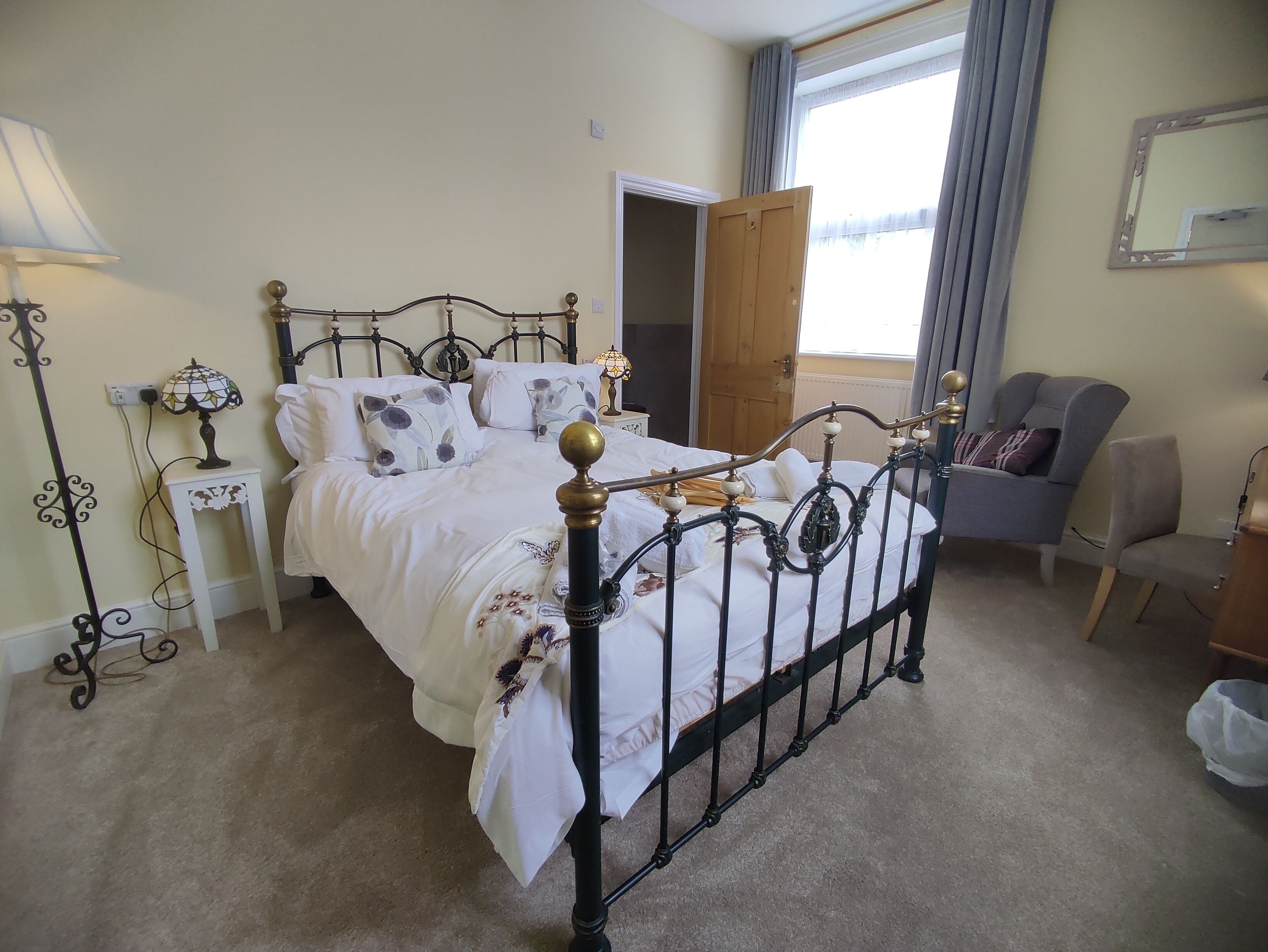 A neatly arranged bedroom with a double bed, bedside tables, a lamp, and a chair.