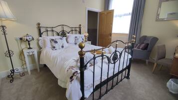 A neatly arranged bedroom with a double bed, bedside tables, a lamp, and a chair.