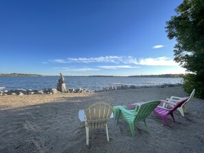 Relax on the lakeside with a serene view, a stone statue, and comfortable seating for two.