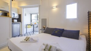 Una camera d'albergo con un letto, un tavolino con una ciotola di frutta, un forno a microonde e un frigorifero.