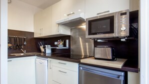 Una cucina moderna con mobili bianchi, un forno a microonde in acciaio inossidabile, un tostapane e una lavastoviglie.