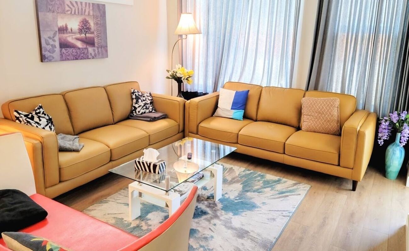 A living room with two tan sofas, a glass coffee table, and a red chair.