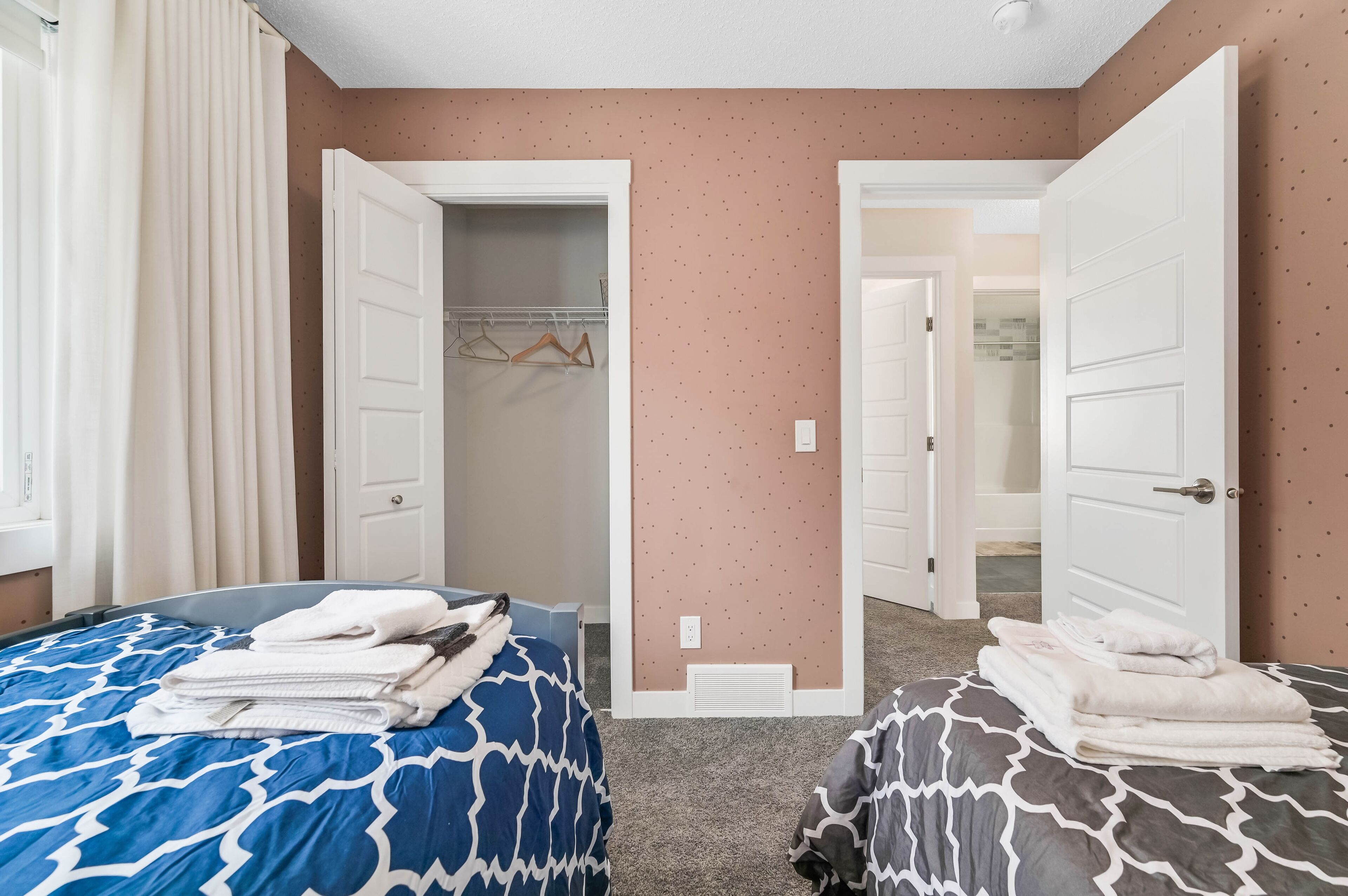 A bedroom with two beds, a closet, and a bathroom visible through an open door.