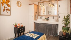 Un dormitorio con una cama, un aparador, una tocador con espejo y un ventilador de techo.
