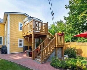 A two-story house with a wooden deck and a staircase leading to the upper floor. - Sunny Home (Charlottetown)