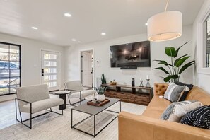 A modern living room with a sofa, armchair, coffee table, and TV.