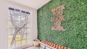A room with a large window, a bench, and a wall with a green leafy wall and a motivational quote.