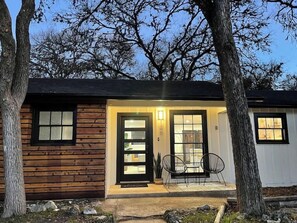 A log cabin with a front porch, two chairs, and a small table.