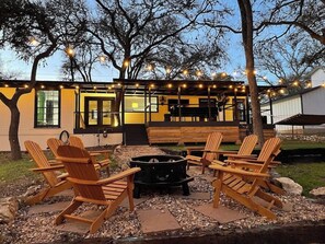 An outdoor seating area with Adirondack chairs, a fire pit, and string lights. - LUXURY BEDDING _ 1 Mi. to Square/Campus (San Marcos)
