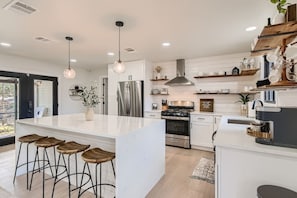 A modern kitchen with a central island, bar stools, stainless steel appliances, and a large window. - LUXURY BEDDING _ 1 Mi. to Square/Campus (San Marcos)