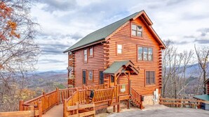 Une cabane en rondins avec un escalier en bois menant à un porche, entourée d’une clôture en bois et offrant une vue panoramique.