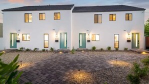 Ein modernes, zweistöckiges Gebäude mit einer symmetrischen Fassade und gleichmäßig verteilten Fenstern, sowie einer Zuwegung mit Kies.