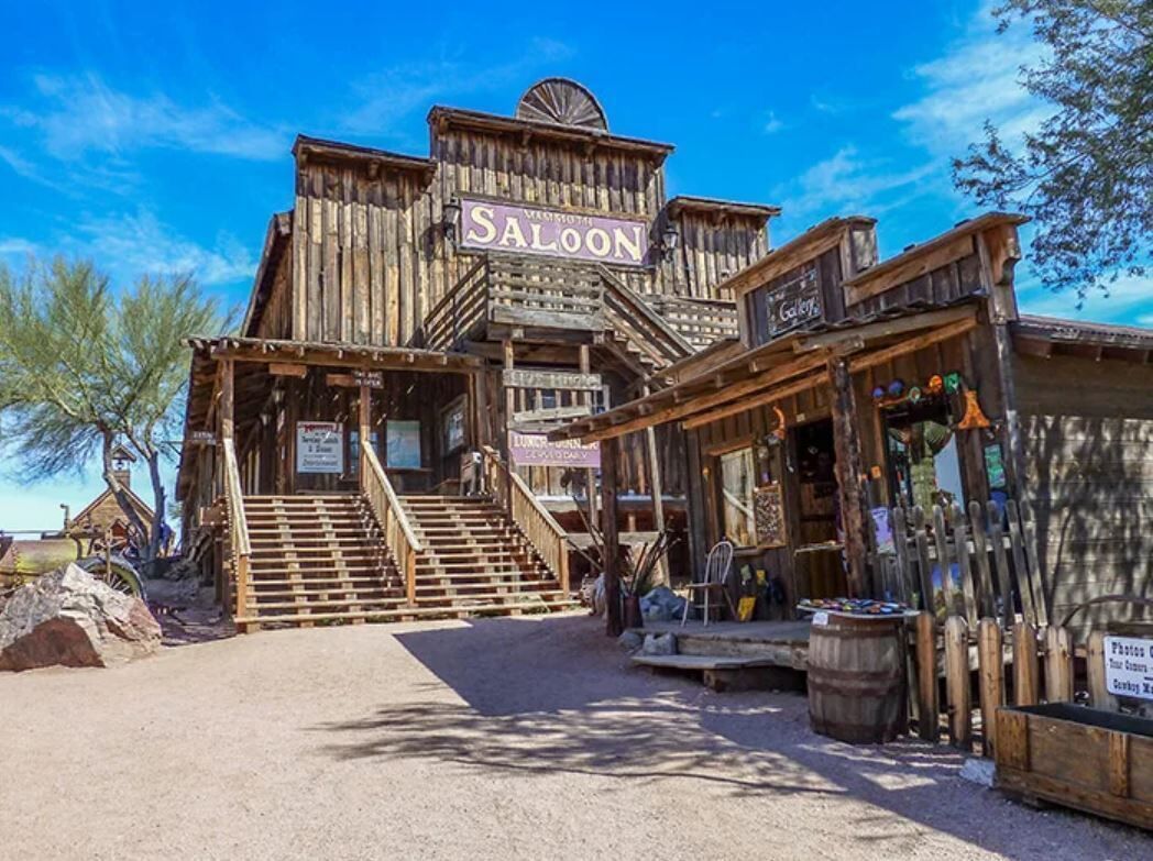 Un edifici de fusta amb un rètol que diu "Saloon" i una escala que condueix a l'entrada.