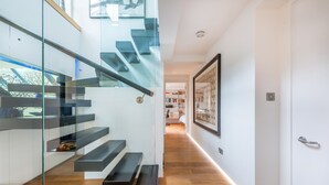 A modern staircase with glass railings and wooden steps leading to a second floor. - Luxe 3b/3b duplex w/ terrace, BBQ & parking. Near Kings Cross & central London. (London)