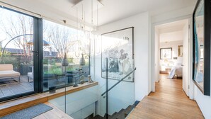 A modern interior with a glass staircase leading to a balcony, a wooden floor, and a view of the outdoors. - Luxe 3b/3b duplex w/ terrace, BBQ & parking. Near Kings Cross & central London. (London)