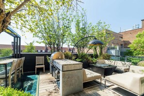 Un patio exterior con una parrilla, asientos y una piscina.