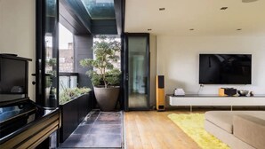 A modern living room with a large TV, a sofa, and a potted plant. - Luxe 3b/3b duplex w/ terrace, BBQ & parking. Near Kings Cross & central London. (London)
