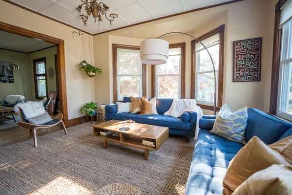A living room with a blue sofa, wooden coffee table, and a chandelier.