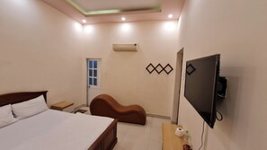 Een slaapkamer met een bed, een televisie, een airconditioning en een wandlamp.