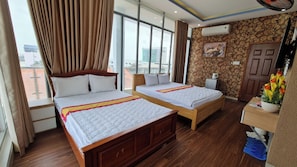 Een hotelkamer met twee houten bedden, grote ramen, uitzicht op de stad en een decoratieve muur.