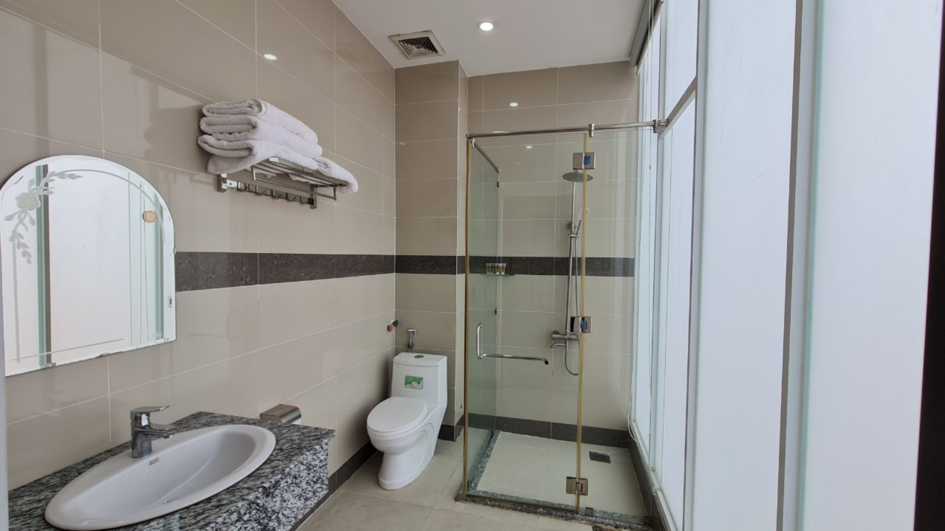 A modern bathroom with a glass-enclosed shower, a sink with a marble countertop, and a toilet.