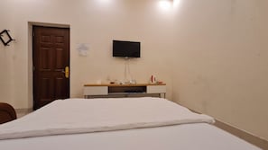Een slaapkamer met een bed, een bureau met een flatscreen televisie, een deur en een bordje aan de muur.