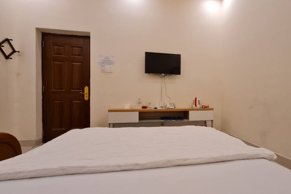 Une chambre à coucher avec un lit, un bureau doté d’un téléviseur à écran plat, une porte et un panneau fixé au mur.