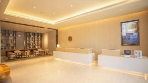 A hotel reception area with a reception desk, seating area, and a television screen.