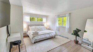 A bedroom with a bed, bedside tables, a mirror, a desk, and a potted plant. - Walk to Shops & Dining – Renovated Gem (Sister Bay)