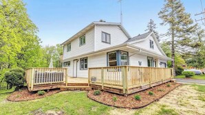 A two-story house with a front deck and a garage. - Walk to Shops & Dining – Renovated Gem (Sister Bay)