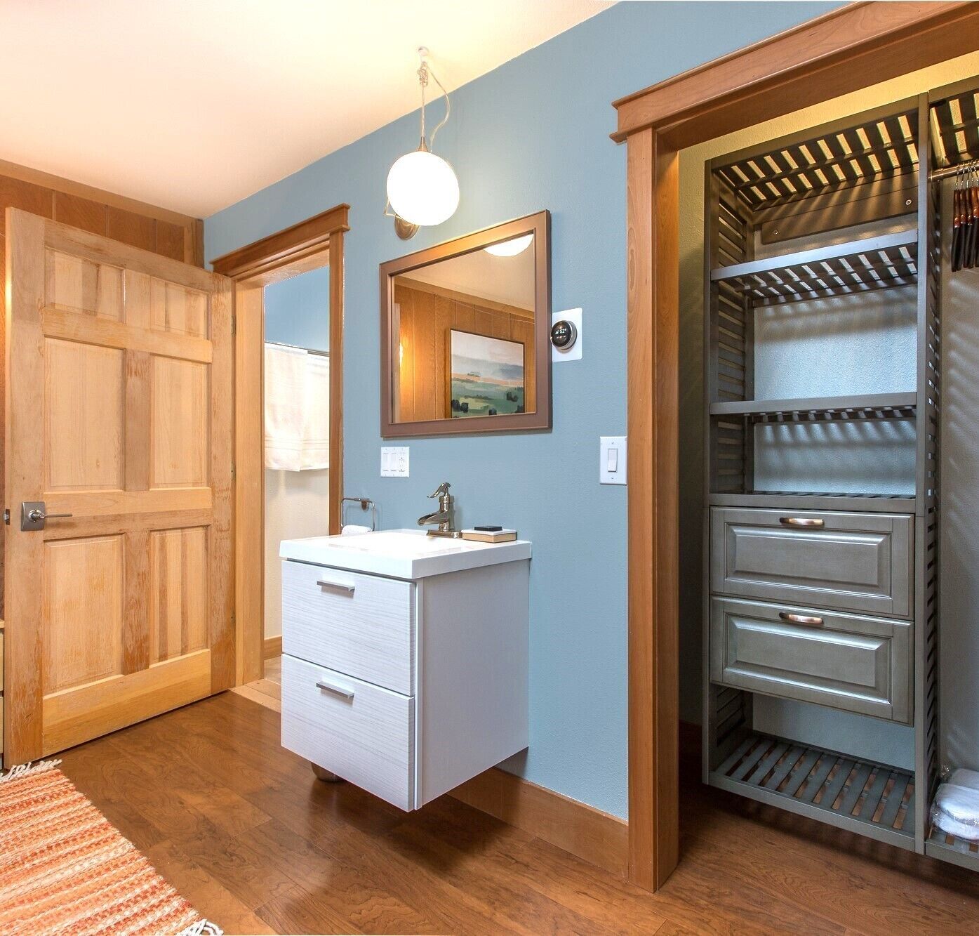 A bathroom with a wooden vanity, a mirror, and a towel rack.