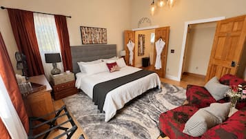 A bedroom with a bed, bedside tables, a dresser, a red sofa, and a wooden wardrobe.