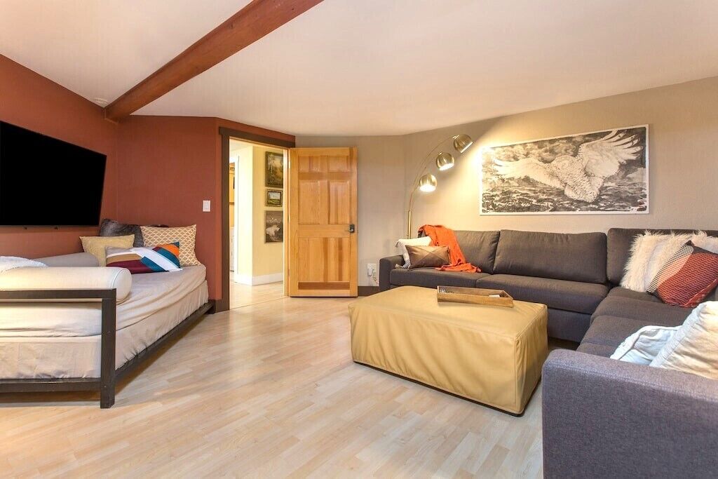 A room with a bed, a sofa, a small table, and a painting on the wall.
