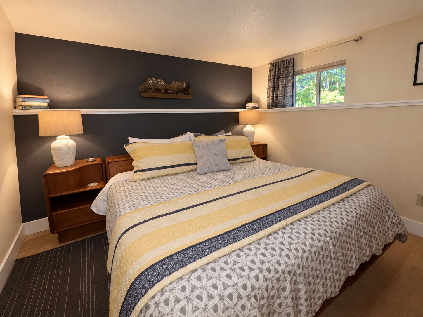 A bedroom with a bed, bedside tables, lamps, and a window with curtains.
