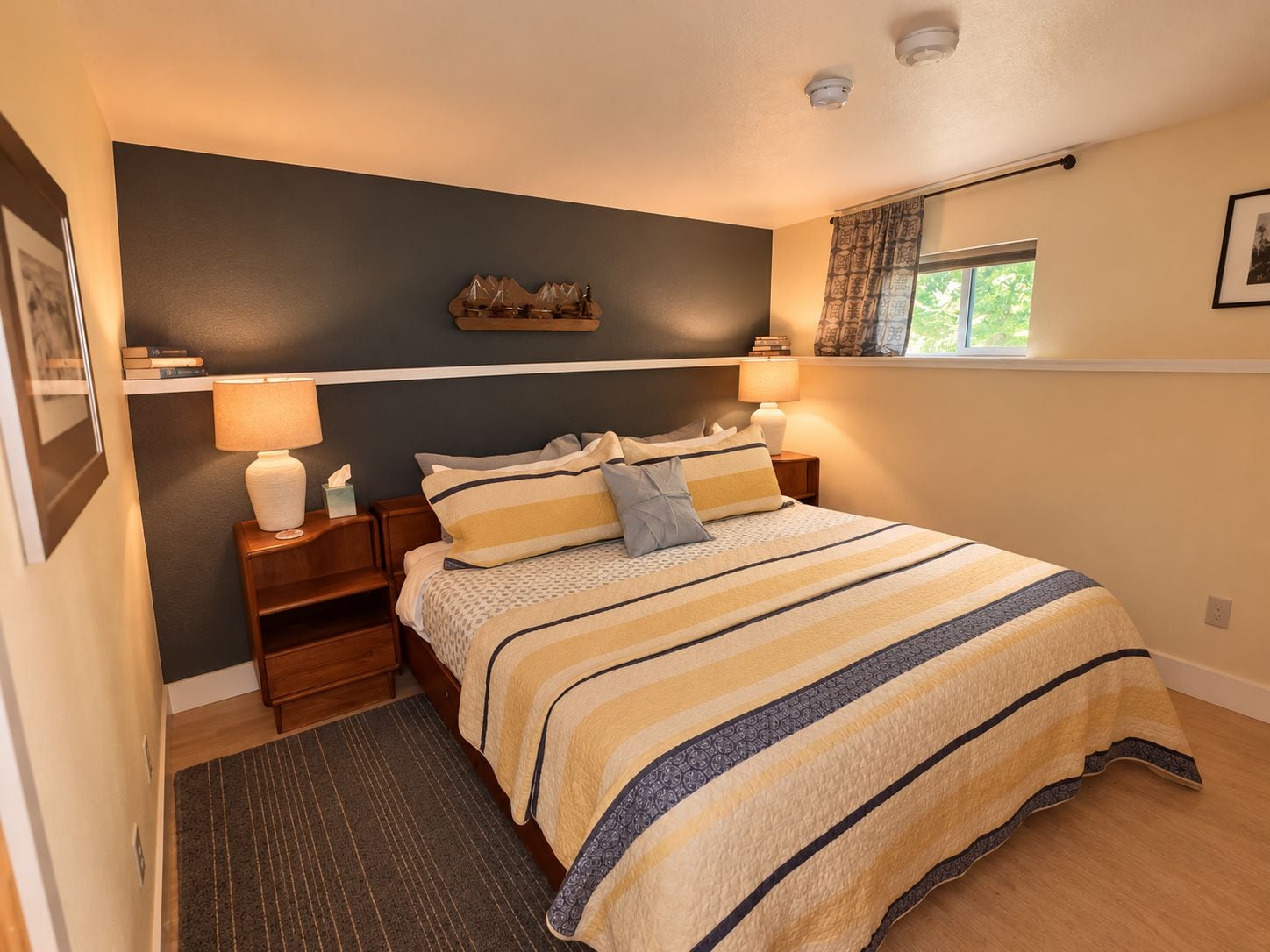 Une chambre à coucher avec un lit, des tables de chevet, une fenêtre avec des rideaux et une étagère murale contenant des livres.