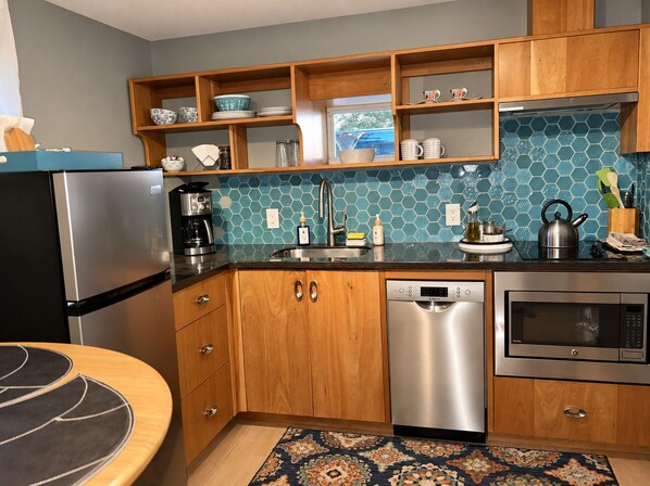 Una cocina con armarios de madera, un refrigerador de acero inoxidable, un lavavajillas y un microondas.