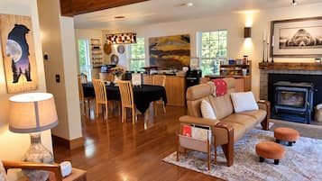 A cozy living room with a fireplace, wooden furniture, and a dining area with a view of the outdoors.