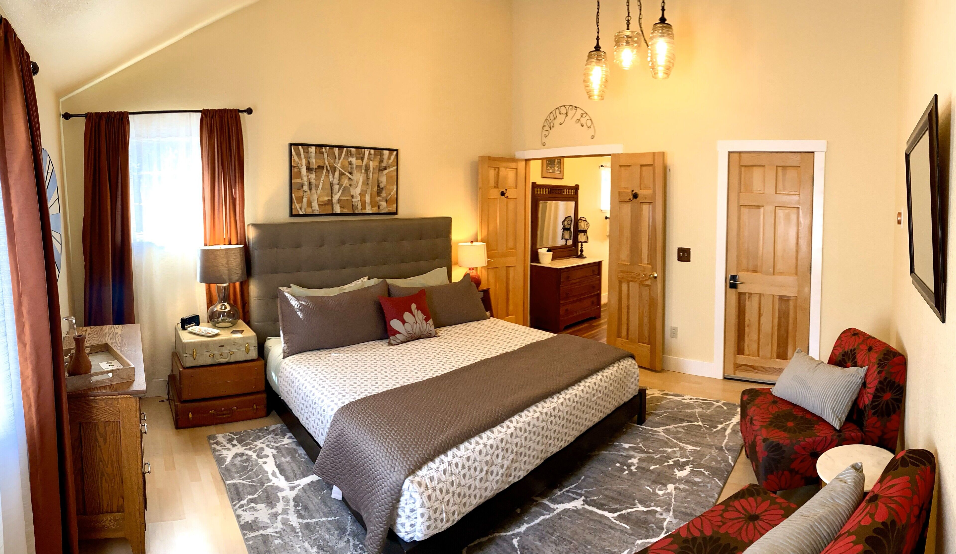 Une chambre à coucher avec un lit, des tables de chevet, une commode, un canapé et une porte.