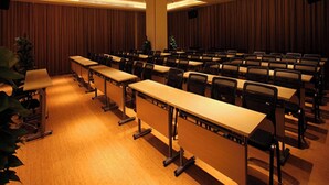 A conference room with rows of tables and chairs, a podium, and a ceiling with recessed lighting. - Ji Hotel (shanghai Hongqiao International Exhibiti (Shanghai)