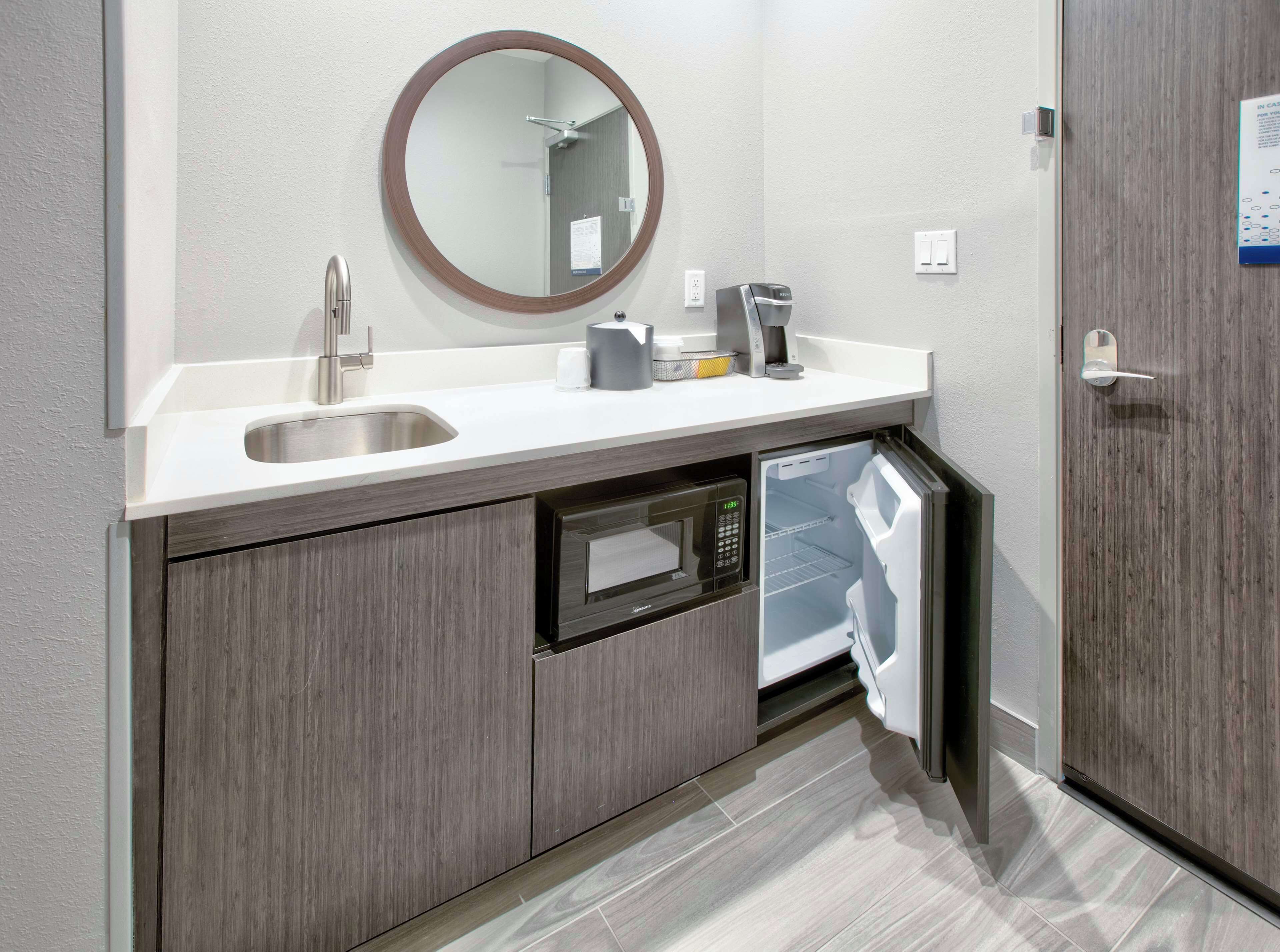 A modern bathroom with a built-in sink, a mirror, a coffee machine, and a dishwasher.