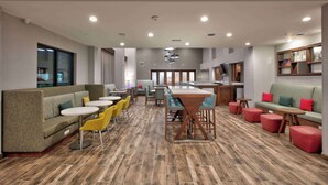 Een modern interieur met een lange eettafel, meerdere zitmogelijkheden waaronder banken en stoelen, en een keuken op de achtergrond.