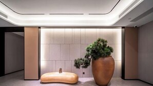 A modern lobby with a minimalist design, featuring a large potted plant and a unique wooden bench. - JI Hotel (Chongqing North Railway Station) (Chongqing)